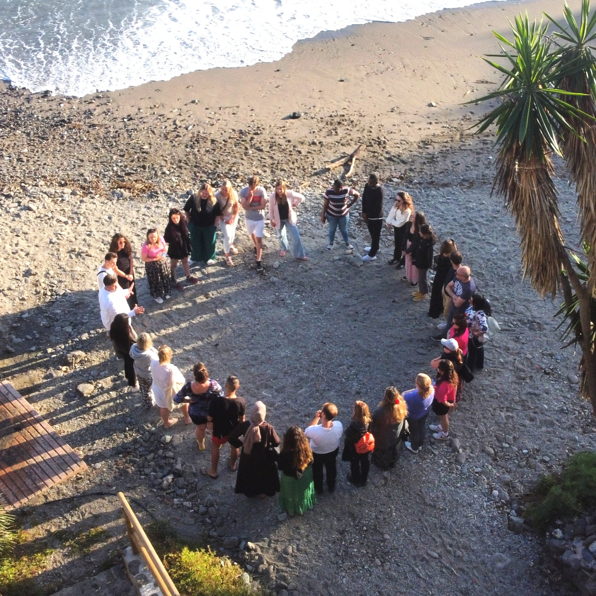 A group in a circle by the beach having a group discussion